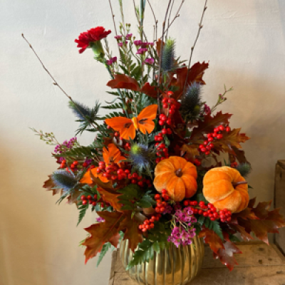 Wild Berry Arrangement - Enjoy this beautiful winter’s arrangement displayed in a gold pot with beautiful reds, purple and oranges. Flowers to be wild and wintery looking. Finished off with some seasonal picks.