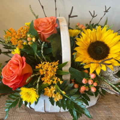 Rustic Basket - Front facing arrangement. Flowers arranged in oasis using a Trug basket or similar as container. Flower selection Rustic shades - oranges and yellows. Twigs used to create rustic effect.